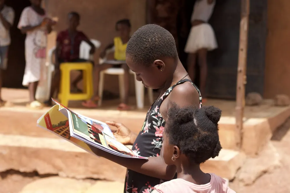 A girl reading a Mildheart comic book with a younger child
